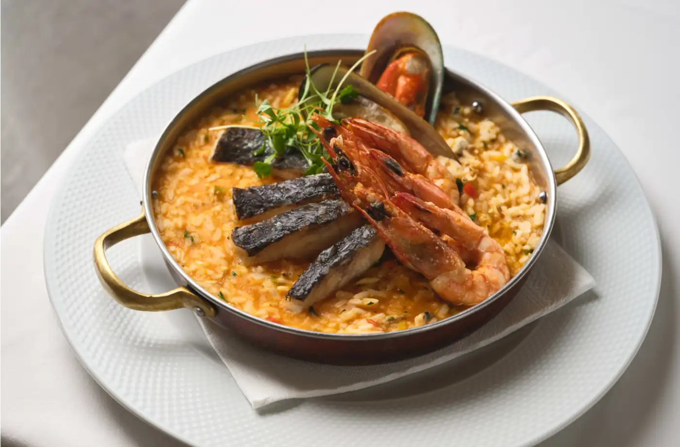 Ein kunstvoll angerichtetes Meeresfrüchte-Risotto im Restaurant Meerblick, mit Garnelen, Muscheln und frischem Kräutern.