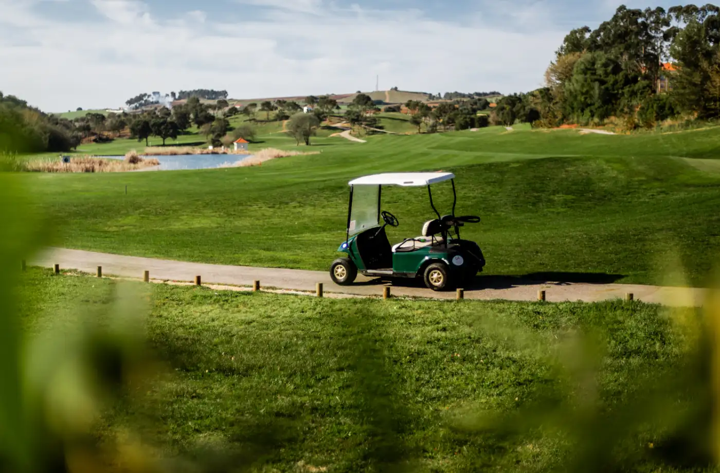 Ein Golfcart steht auf dem Weg einer Golfanlage mit Blick auf den See, ideal für entspannte Golf-Tage in der Natur.