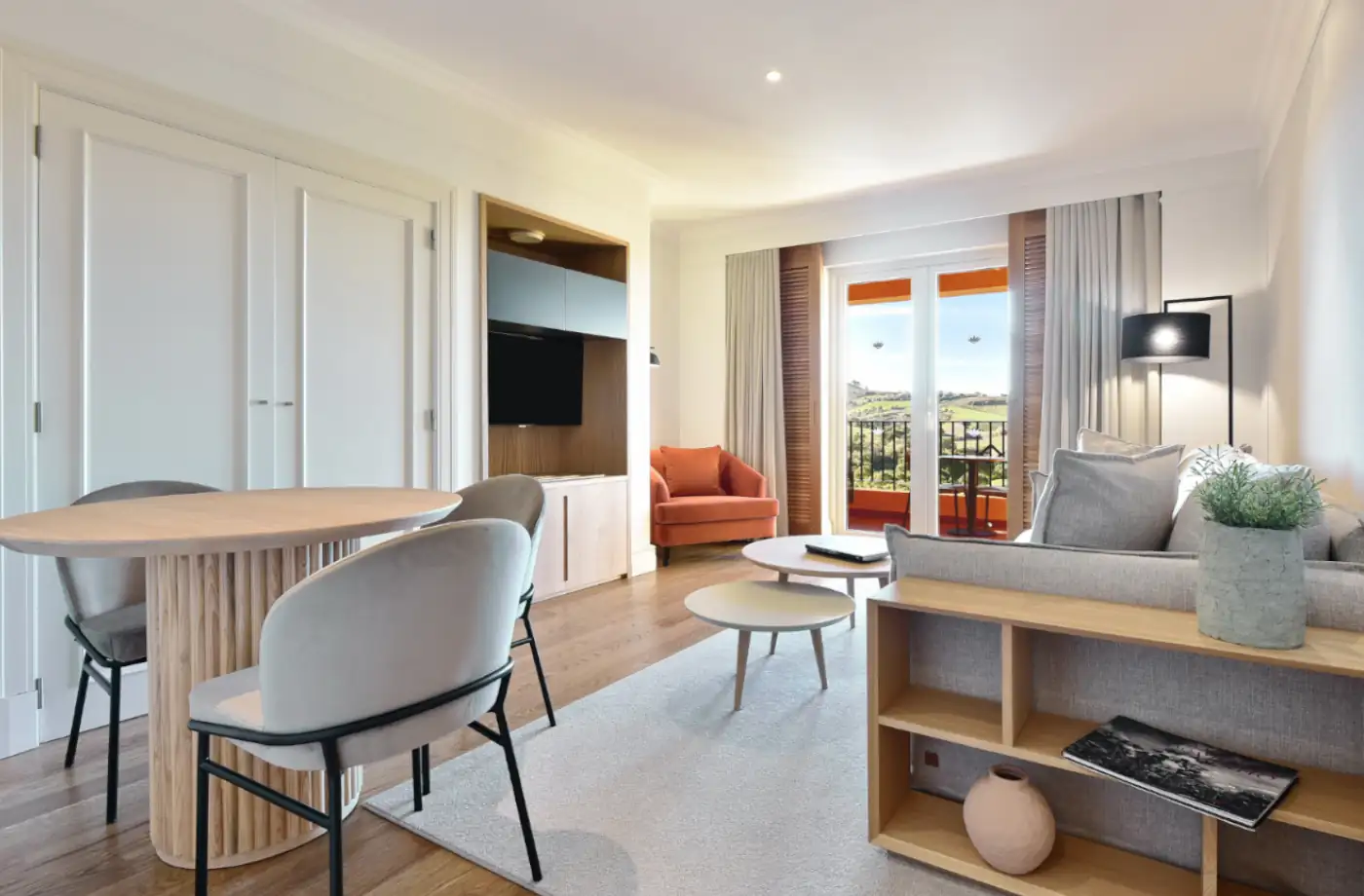 Elegante Suite im Hotel Panorama mit Essbereich, gemütlichem Sofa und Balkon mit Ausblick auf die grüne Landschaft.
