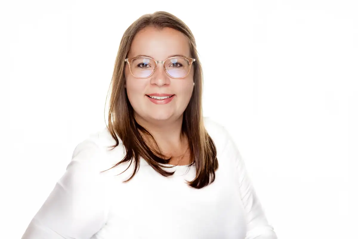 Porträt einer Frau mit Brille in weißem Shirt vor hellem Hintergrund Dominic Scott