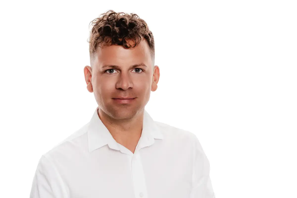Professionelles Porträt eines Mannes in weißem Hemd mit fröhlichem Ausdruck Dominic Scott