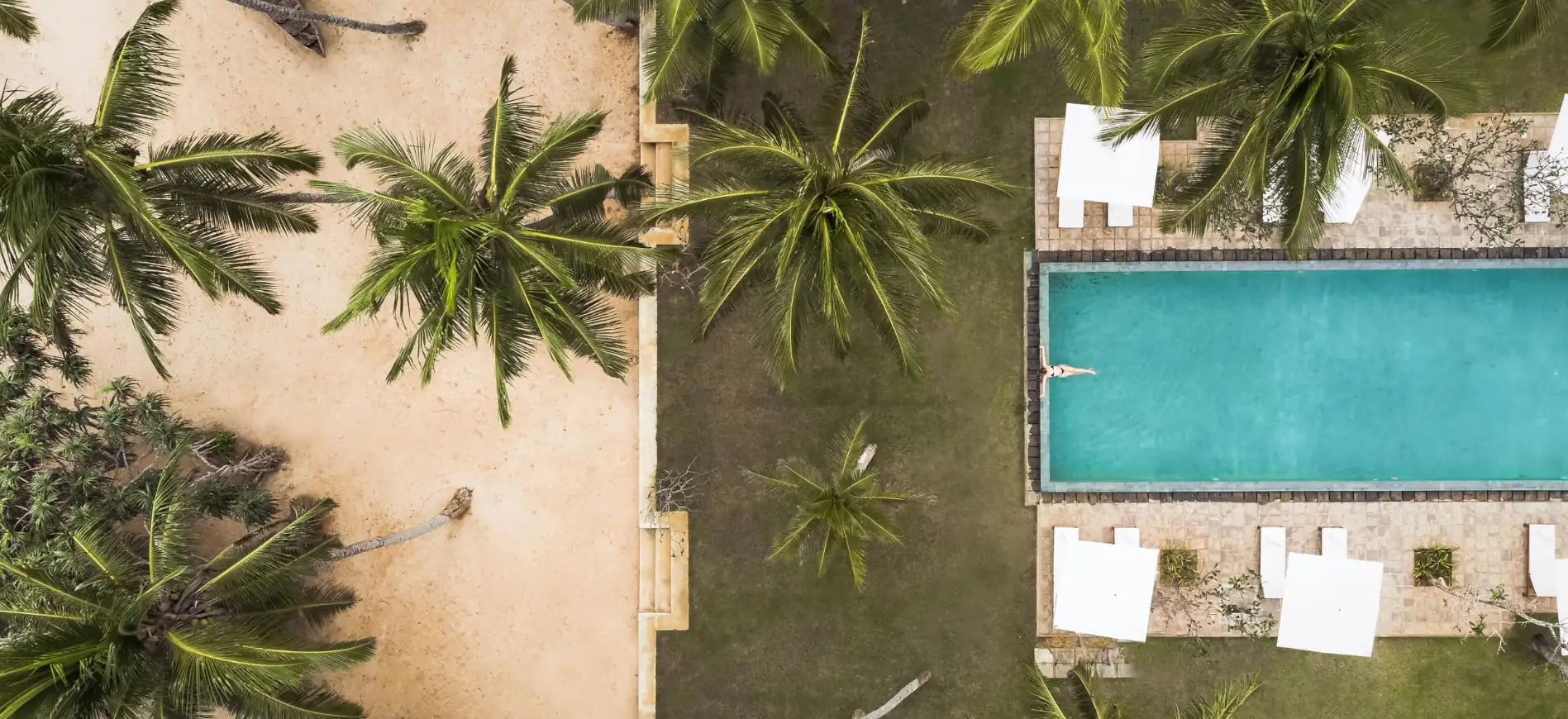 Urlaub im Paradies: Entspannen am Pool unter Palmen Blick auf einen Pool umgeben von Palmen und Liegen, ideal für einen entspannenden Familienurlaub in tropischer Umgebung.