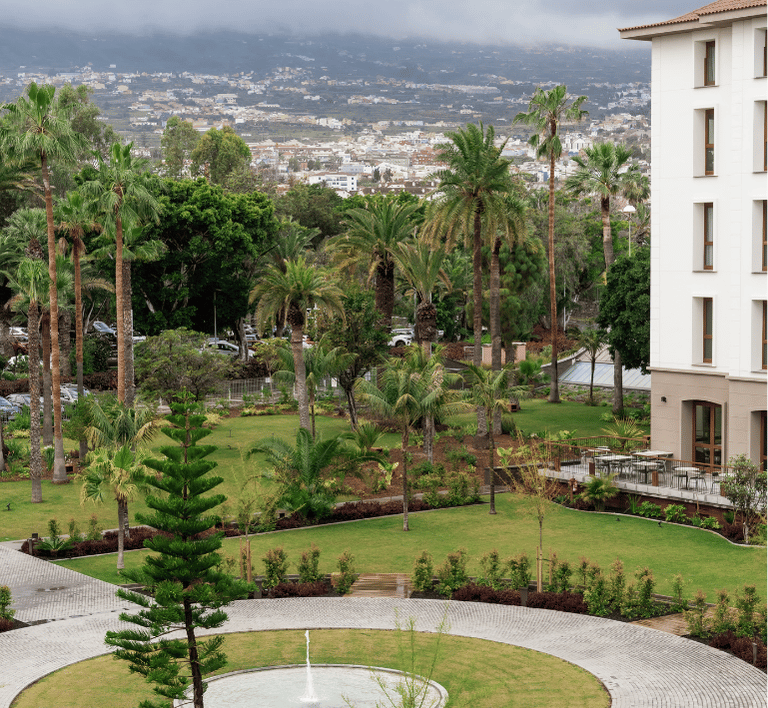 Grüne Gartenlandschaft mit Palmen im Hotelbereich für entspannte Urlaubsmomente Weite Gartenlandschaft mit Palmen und einem zentralen Brunnen im Bereich des Hotels, ideal für entspannende Familientage.