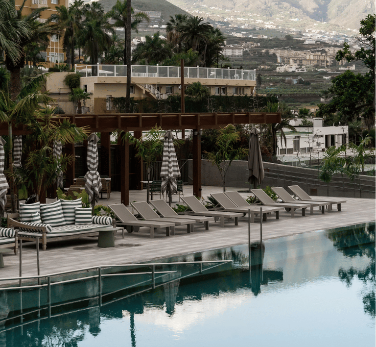 Entspannen am Pool im Hotel Paradies auf der sonnigen Terrasse Entspannende Atmosphäre am Pool des Hotel Paradies, mit Liegen, Sonnenschirmen und Palmen im Urlaubsort.